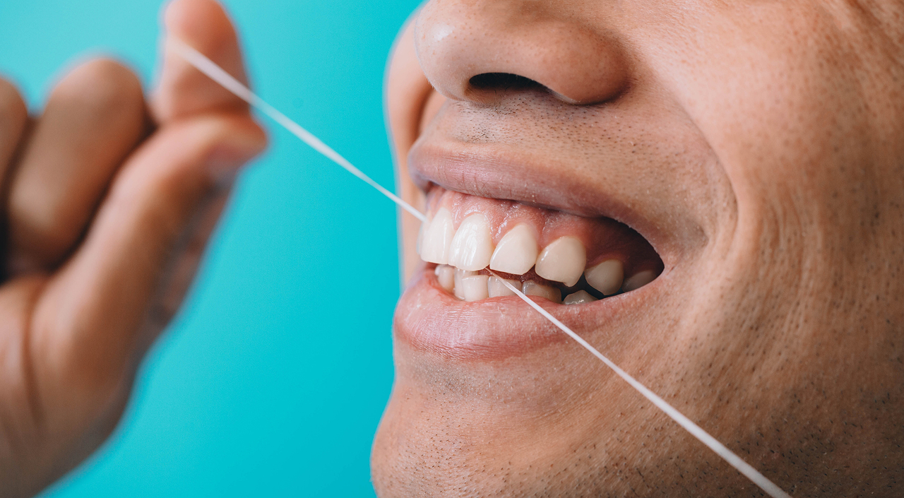 close-up-male-mouth-while-flossing-teeth-with-dentist